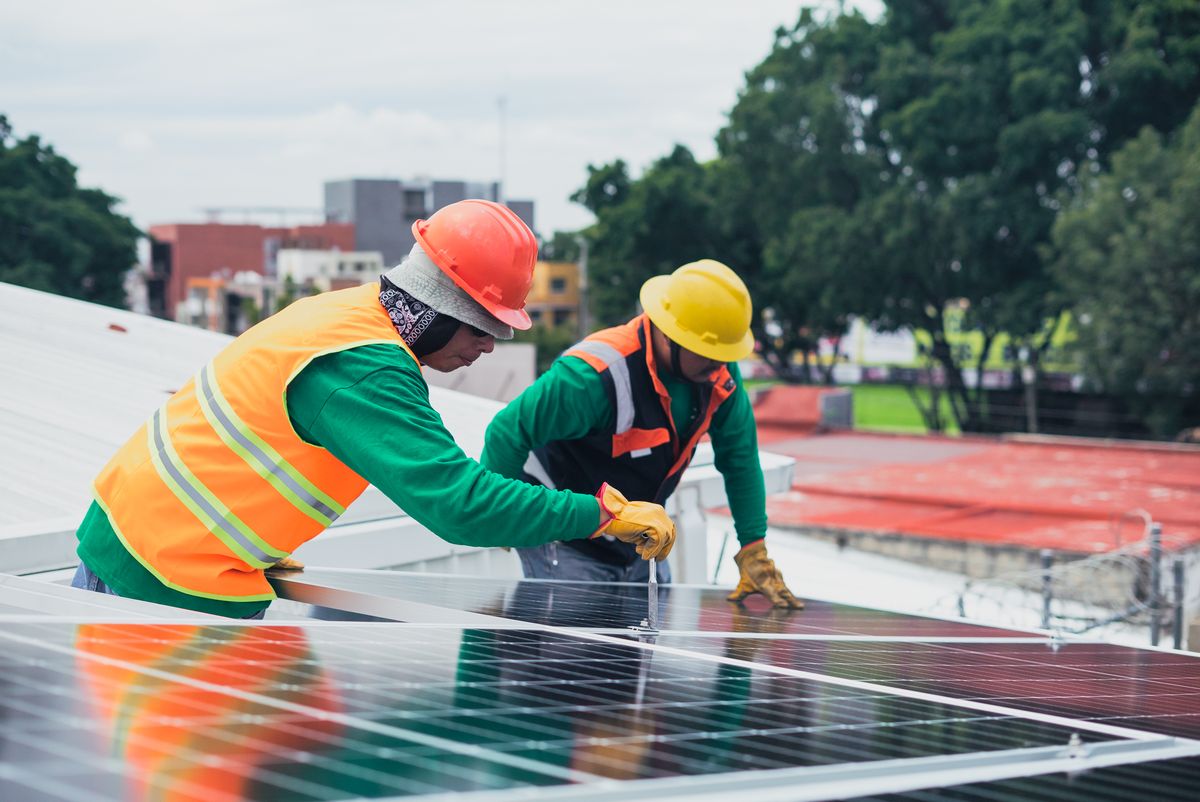 Técnicos instalando painéis solares no telhado